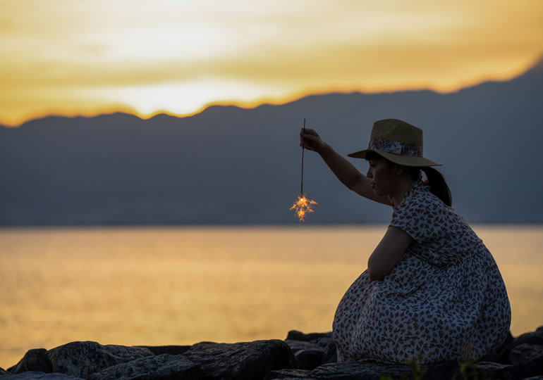 浜辺で線香花火とする女性