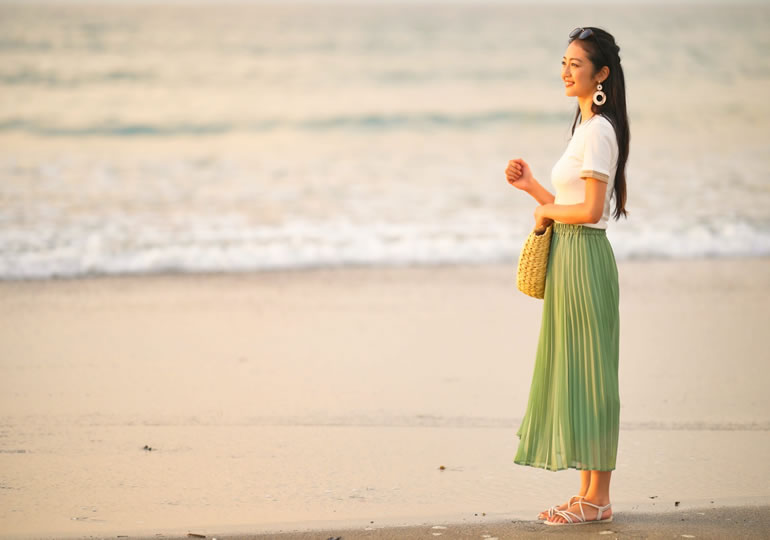 浜辺で夕日を見ている笑顔の女性