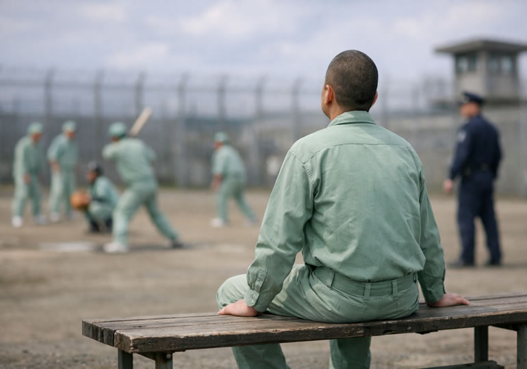 刑務所の運動場で空を見つめる受刑者の男性