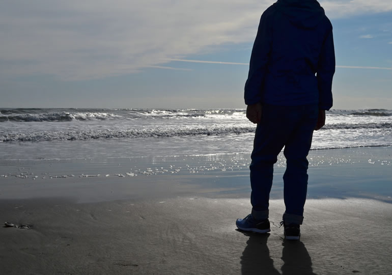 砂浜で海を見つめる男性