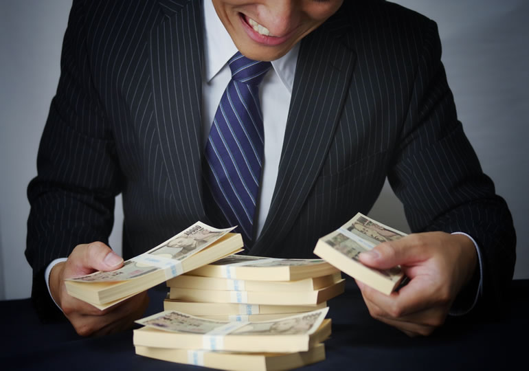 札束を持って笑うサラリーマンの男性
