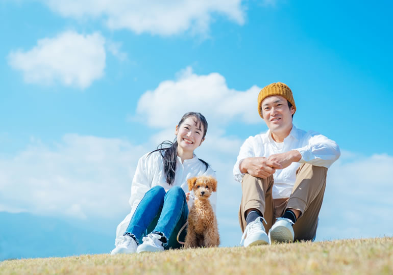 草原で犬の散歩をする夫婦