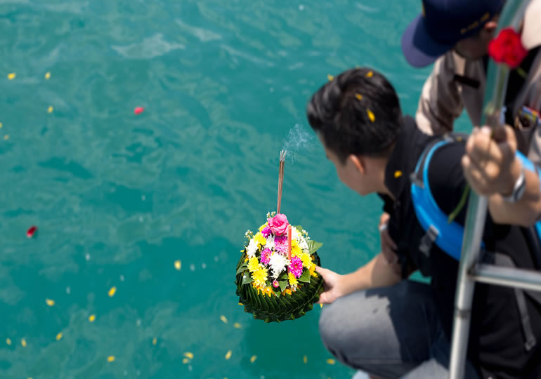 船の上から献花を流すアジア人男性