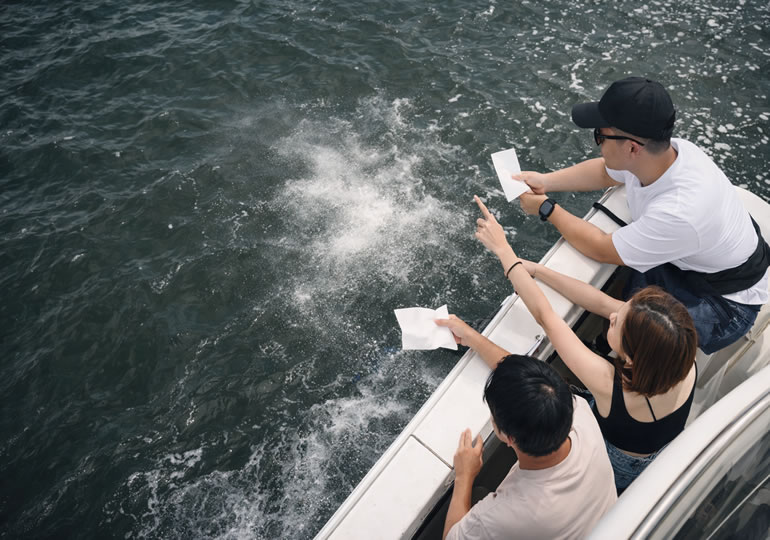 クルーザーから海洋散骨する若い日本人家族