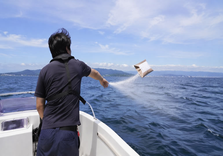 パウダーの遺骨を海に投げ入れている様子