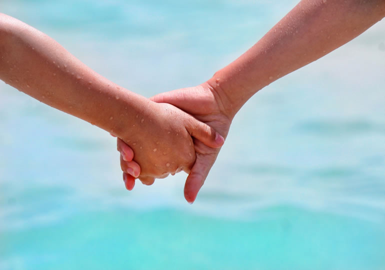 浜辺で手をつなぐ家族