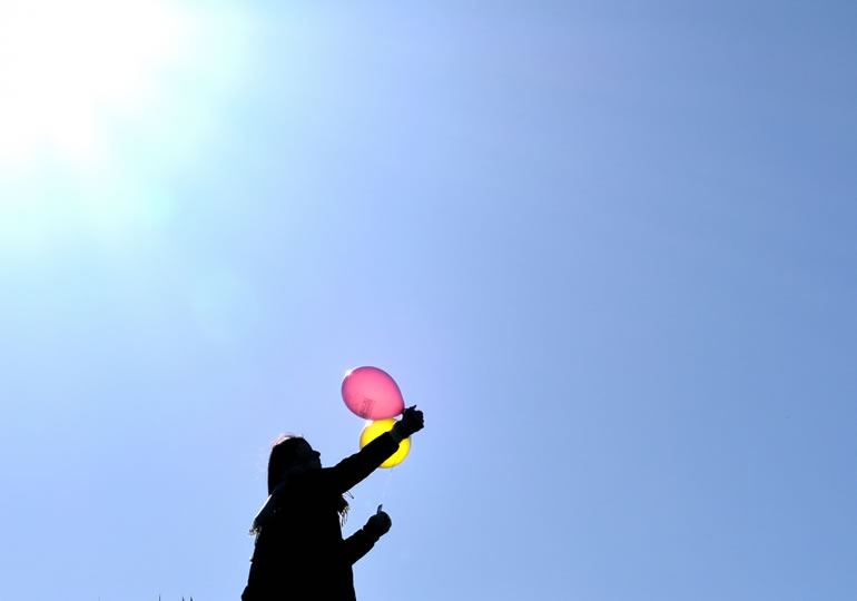 バルーン葬の風船を飛ばす女性
