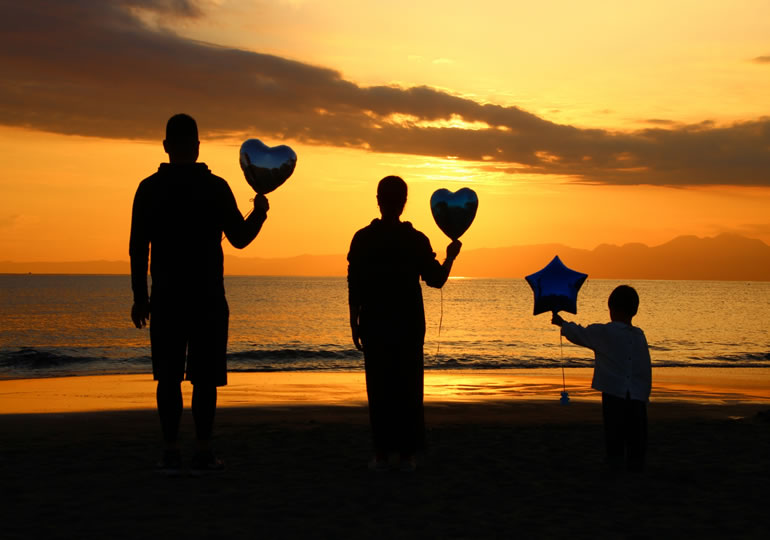浜辺で風船を持っている家族