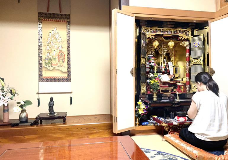 仏間で仏壇を拝む中年女性