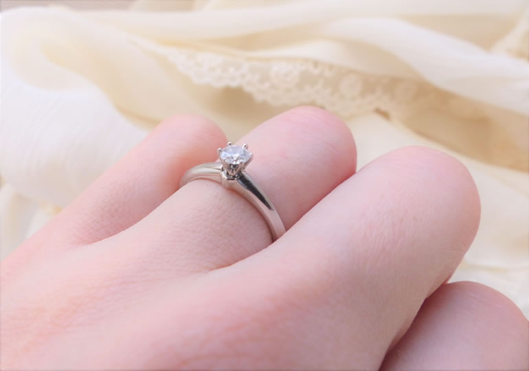 故人の形見として遺骨ダイヤモンドの指輪をはめる女性の指先