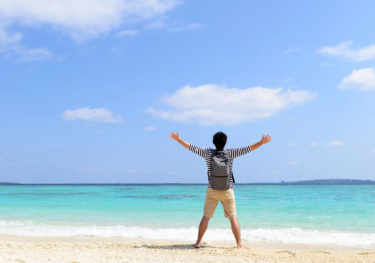 きれいな砂浜で大声を上げる男性の後ろ姿