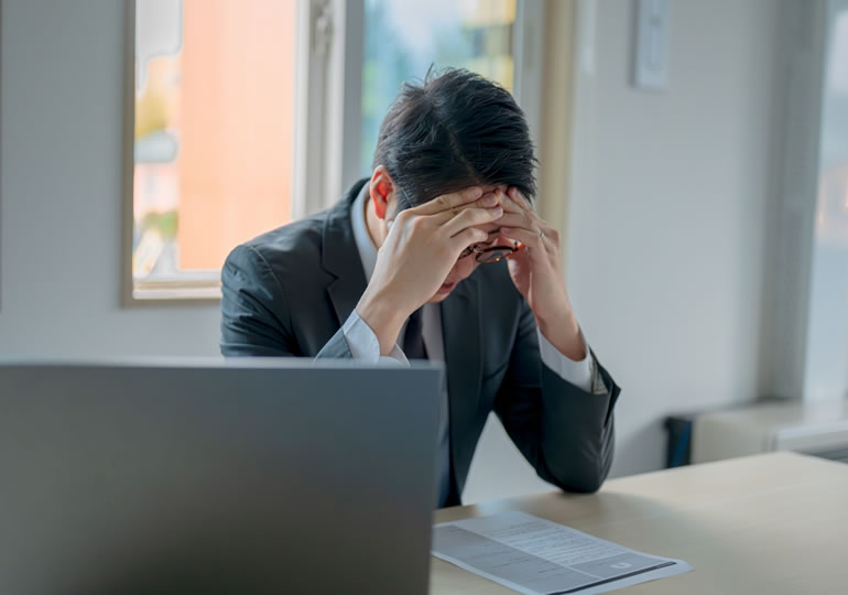 オフィスで頭を抱えて悩む男性
