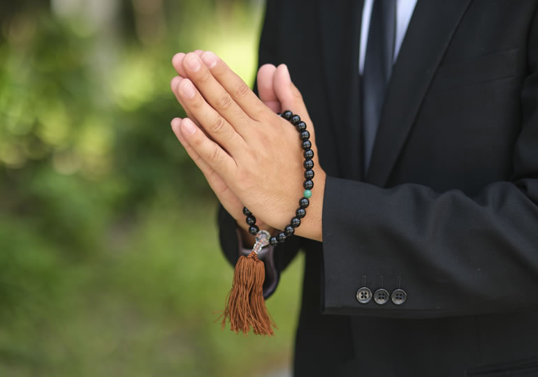 数珠を持って合掌する男性
