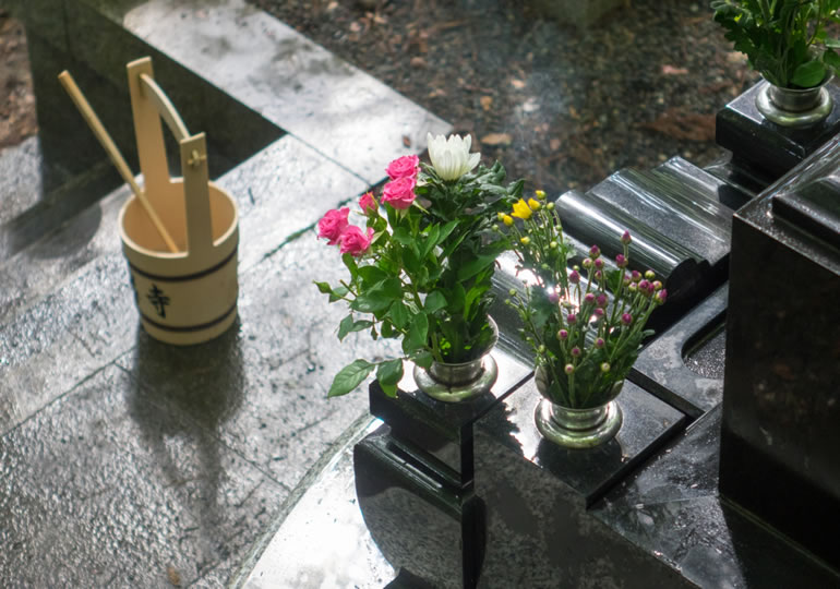 墓参りをして墓石を掃除している風景