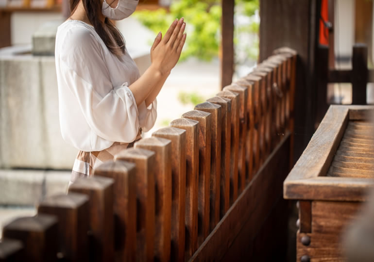 賽銭箱の前で合掌する女性