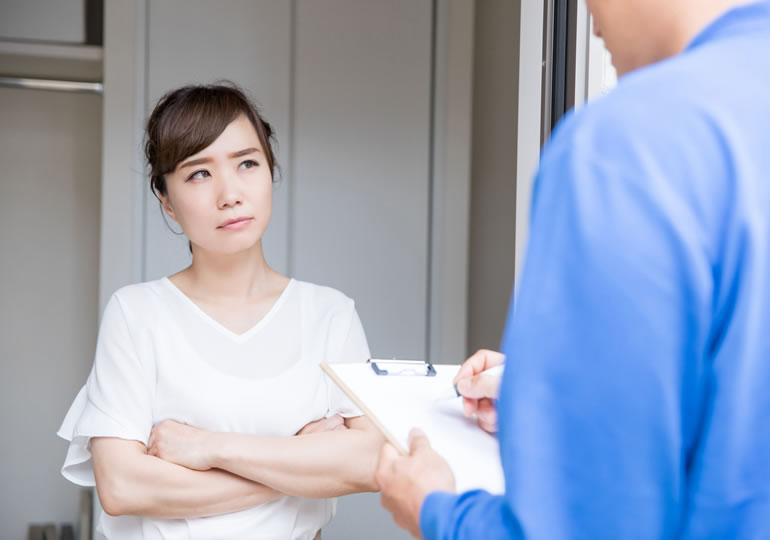 玄関先で遺品整理業者に疑問を抱く若い女性