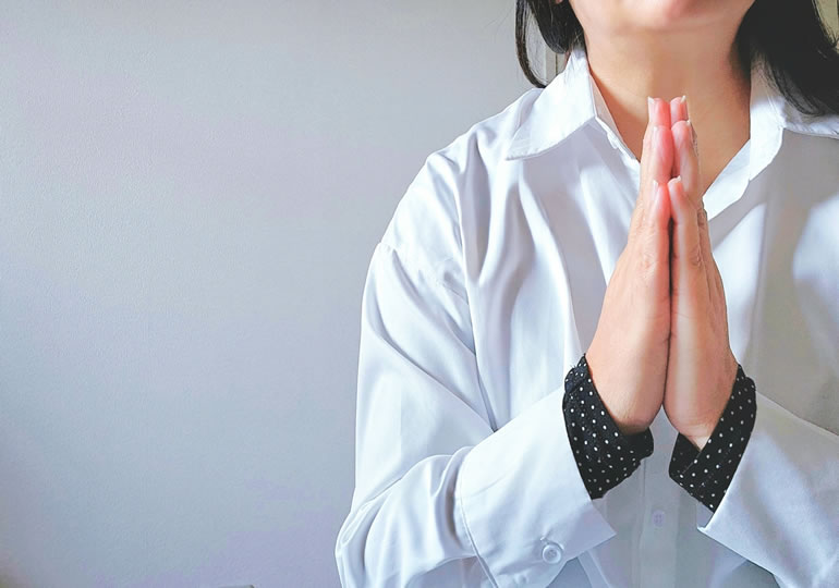 手を合わせて祈る女性