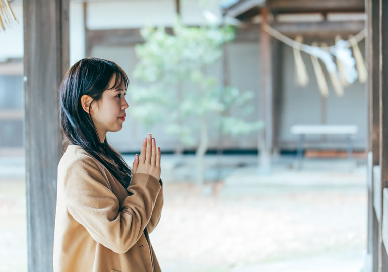 神社で手を合わせる女性の様子