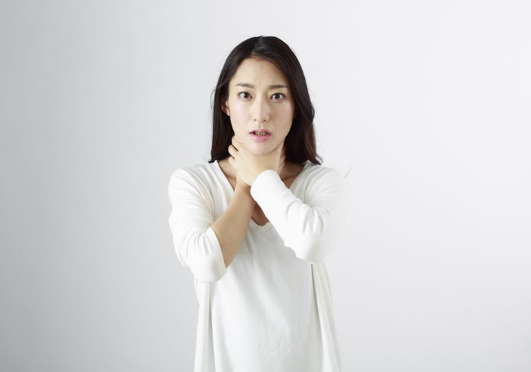 自身の首に手を当てて苦しむ表情をする女性