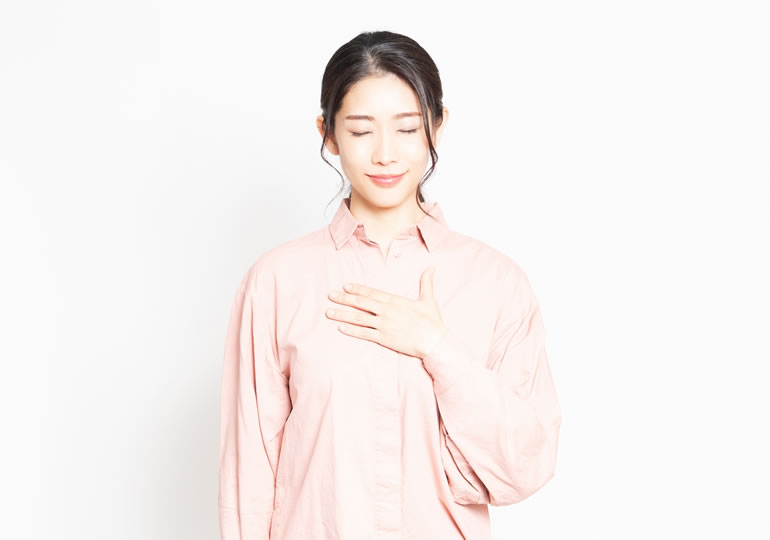 胸に手を当てそっと目を閉じる女性