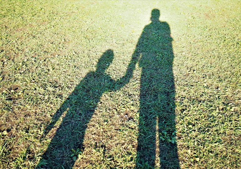 手をつなぐ母子家庭の親子の影
