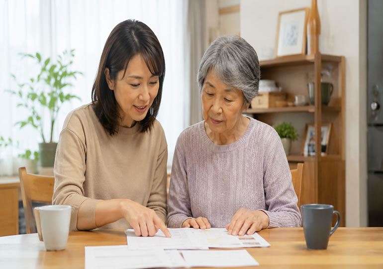 高齢の母親と娘が成年後見制度について書類を確認する様子