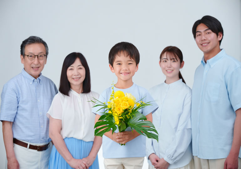 笑顔で花束を持つ男の子と家族