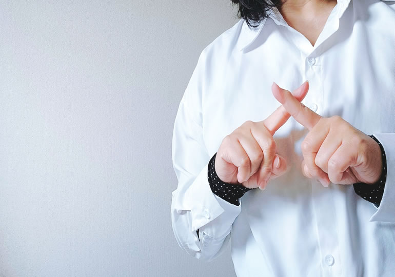 指でバツを作っている女性