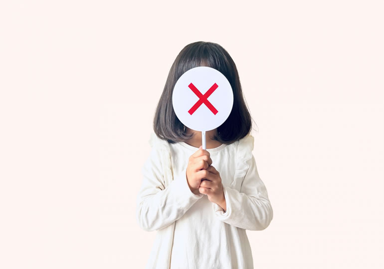 ×のプラカードで顔を隠す小さな子供