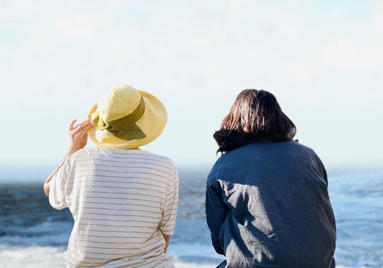 両親の遺骨を散骨した海を見つめる姉妹の後ろ姿