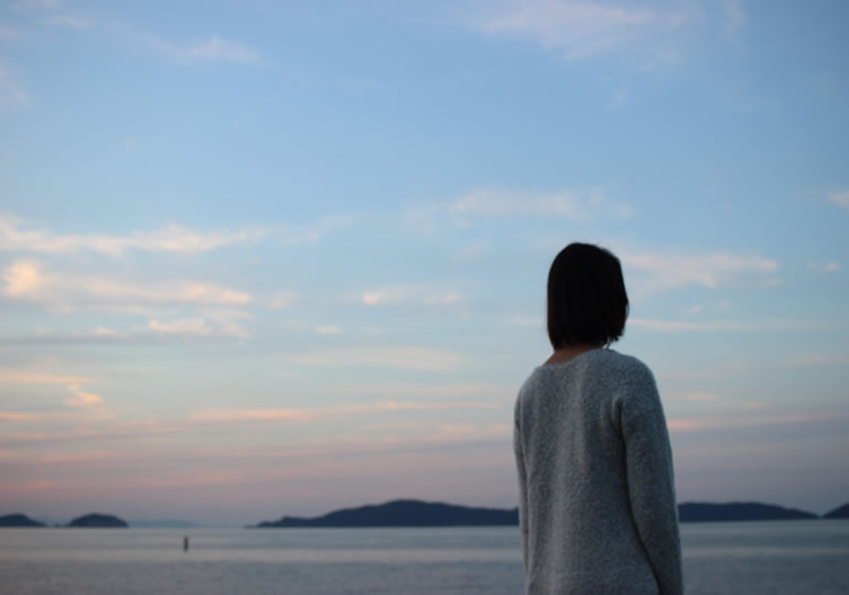 故郷の海を見つめる女性