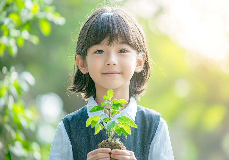 優しい笑顔で苗木を持つ女の子