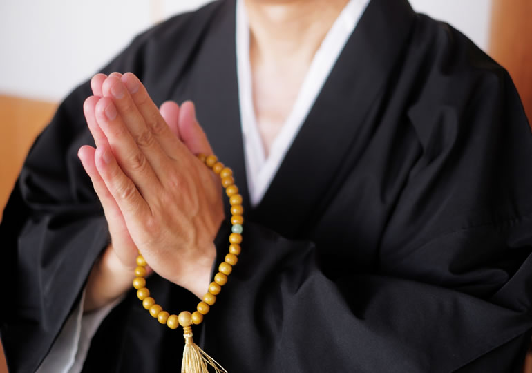 合掌してお経を読む住職