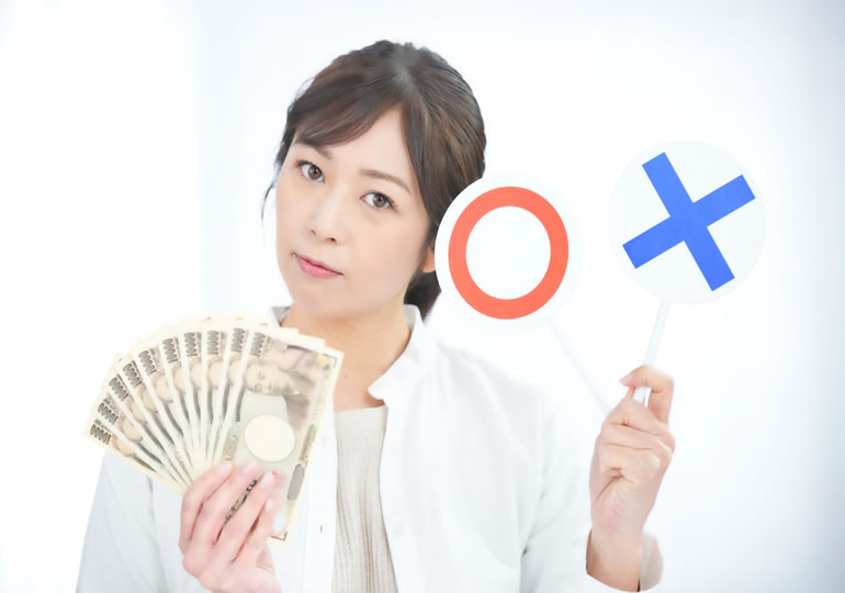 札束とマルバツのプラカードも持っている30代の女性