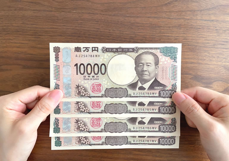 葬祭費給付金を数える女性の手元