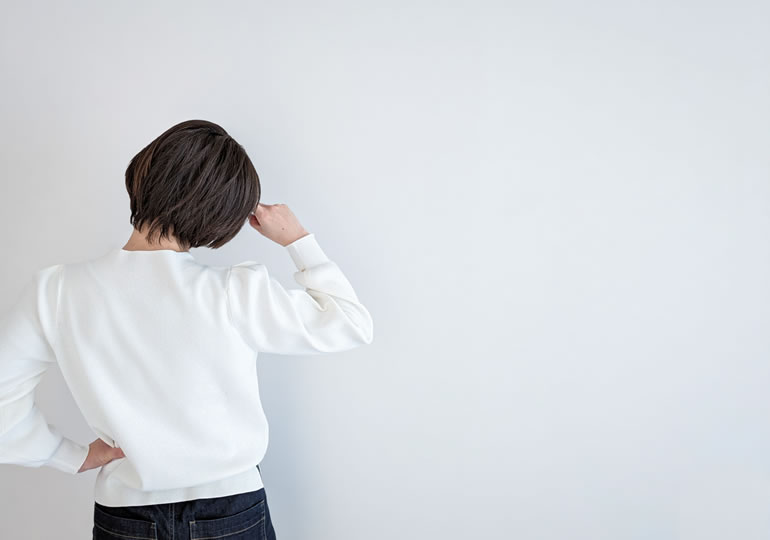 首をかしげる女性の後ろ姿