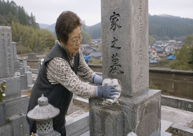 お墓を掃除している高齢女性