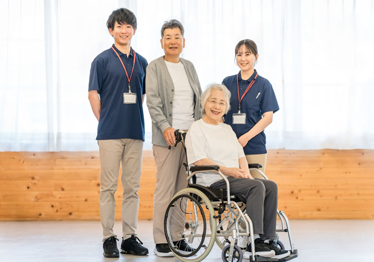 車椅子を押す高齢夫婦と介護施設のスタッフ