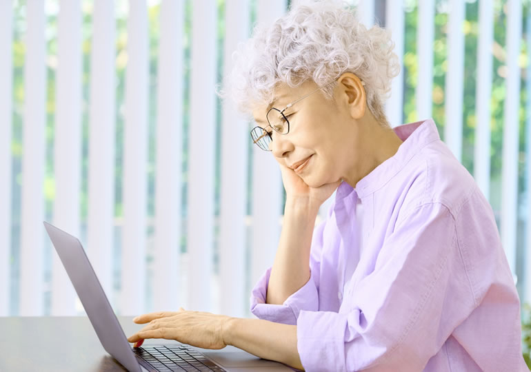 リビングでパソコンを使って終活をする高齢女性