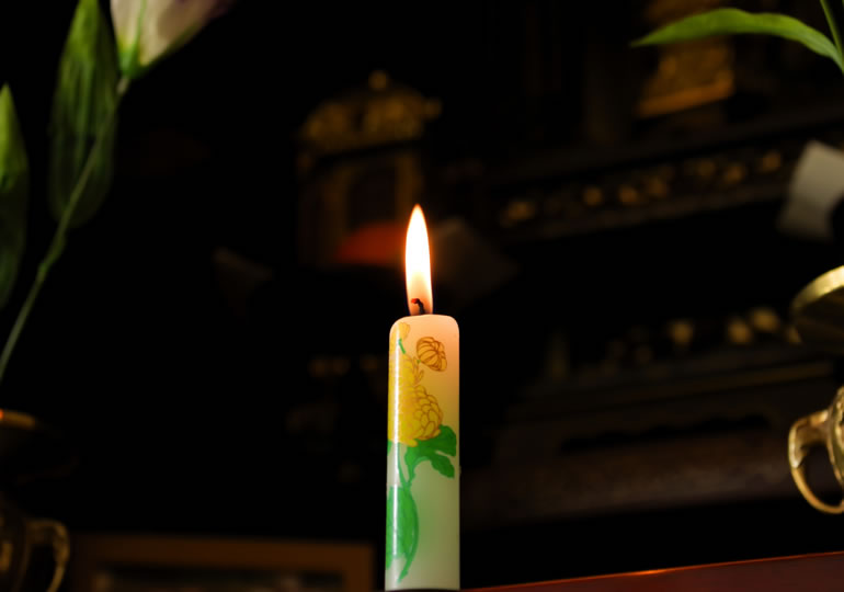 仏壇の前に置かれている火のついたロウソク