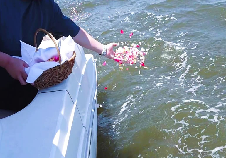 船上から散骨した海に、大量の献花を撒く女性