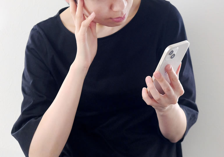 スマホを見つめ悩む女性
