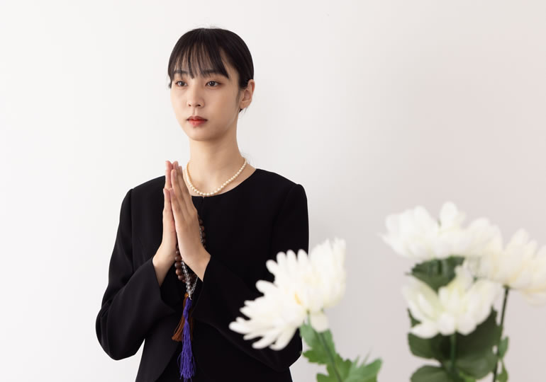 無表情で合掌する女性
