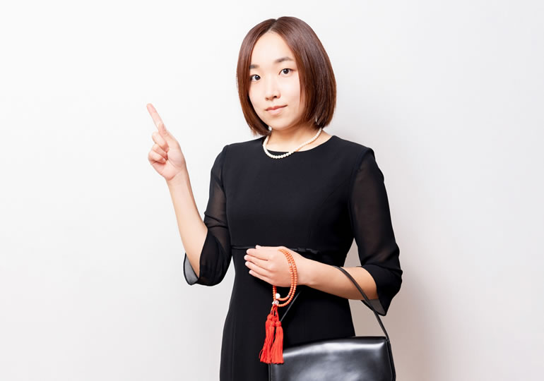 喪服姿でチェックポイントを説明する女性