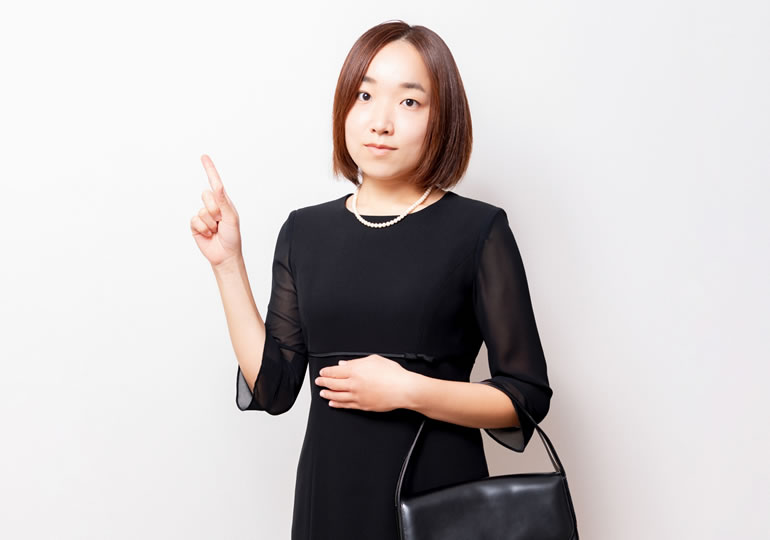 喪服姿で葬儀社の地域活性化を説明する女性