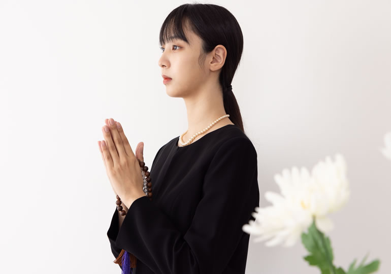 喪服姿で合掌する女性