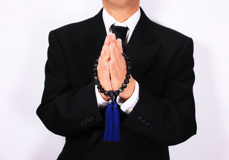 喪服で合掌する男性