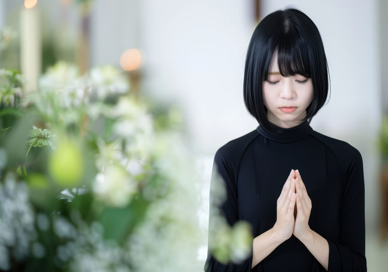葬式で合掌する女性