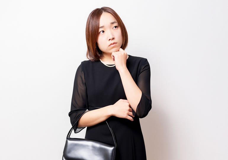 対象者か悩んでいる喪服姿の女性