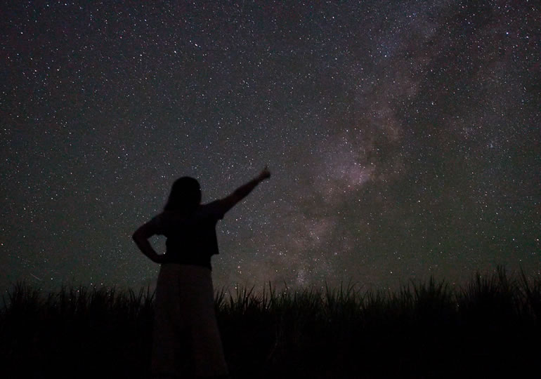 夜空を指さす女性のシルエット画像